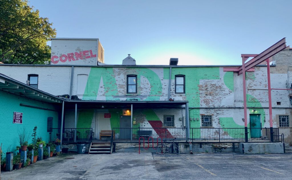 A brick building exterior with with bright green and white paint is seen at dusk