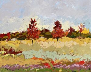 A row of trees in autumn with red leaves amidst an open field