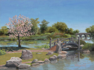 A garden setting on a bright spring day with blossoming trees, bridges and rock features in a pond setting