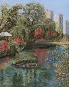 A pond in Lincoln Park in Chicago on a sunny summer day with a willow tree, bushes and grass ridging the water. Some tall residential buildings are seen in the distance