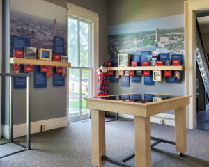 A timeline diorama in an official building with various dates and events shown along two walls on placards. A large mural of historical photos of a mid-size city is on the walls behind the timeline content