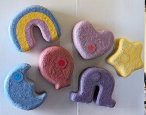 A piece of brightly-colored wall art resembles marshmallow shapes of stars, rainbows, horseshoes, hearts from a popular children's cereal