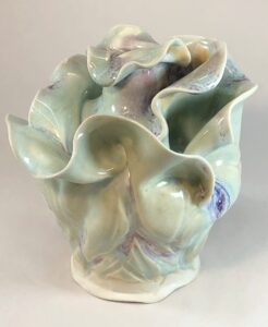 A ceramic sculpture with light green colors that has an almost leafy vegetable-like appearance
